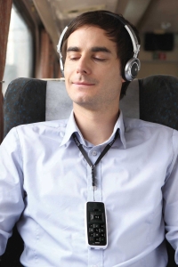 man on train with headphones on listening to audio books from his BookSense DAISY player that is hanging from his neck